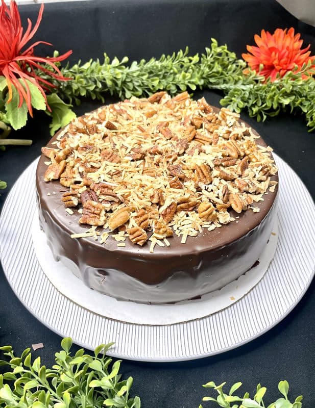 A whole chocolate-ganache cheesecake scattered with toasted pecans and white chocolate.