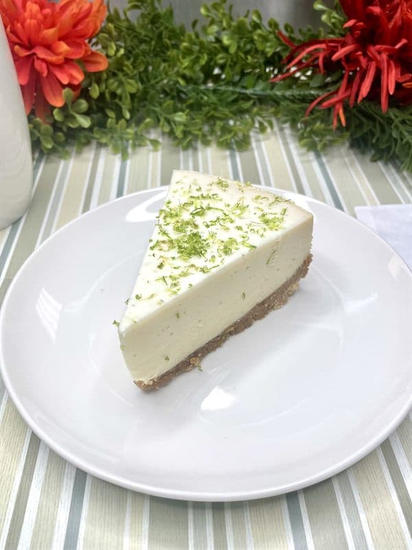 A slice of key lime cheesecake finished with lime zest.