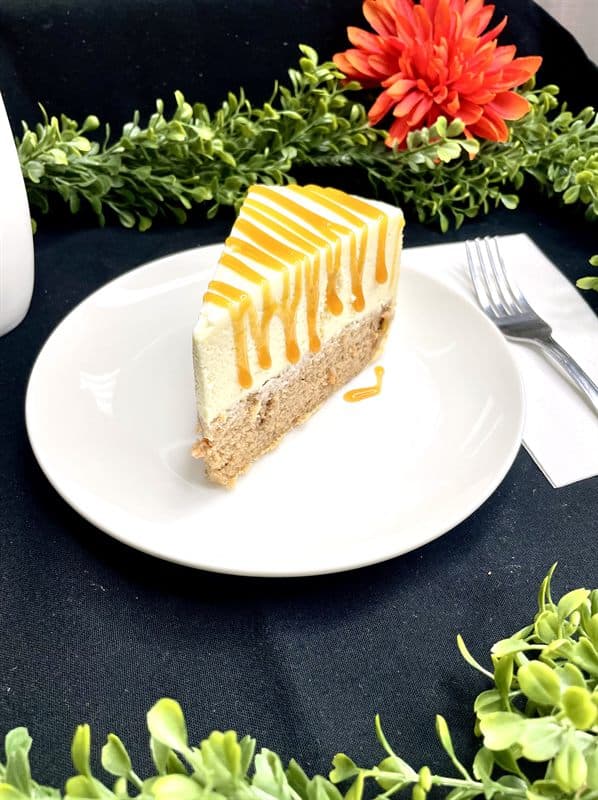 A slice of cheesecake finished with a mango glaze drizzle.