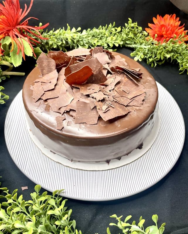 A whole chocolate cheesecake finished with chocolate shards.