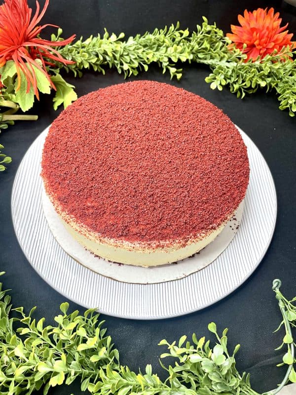 A whole red velvet cheesecake topped with red velvet crumb.